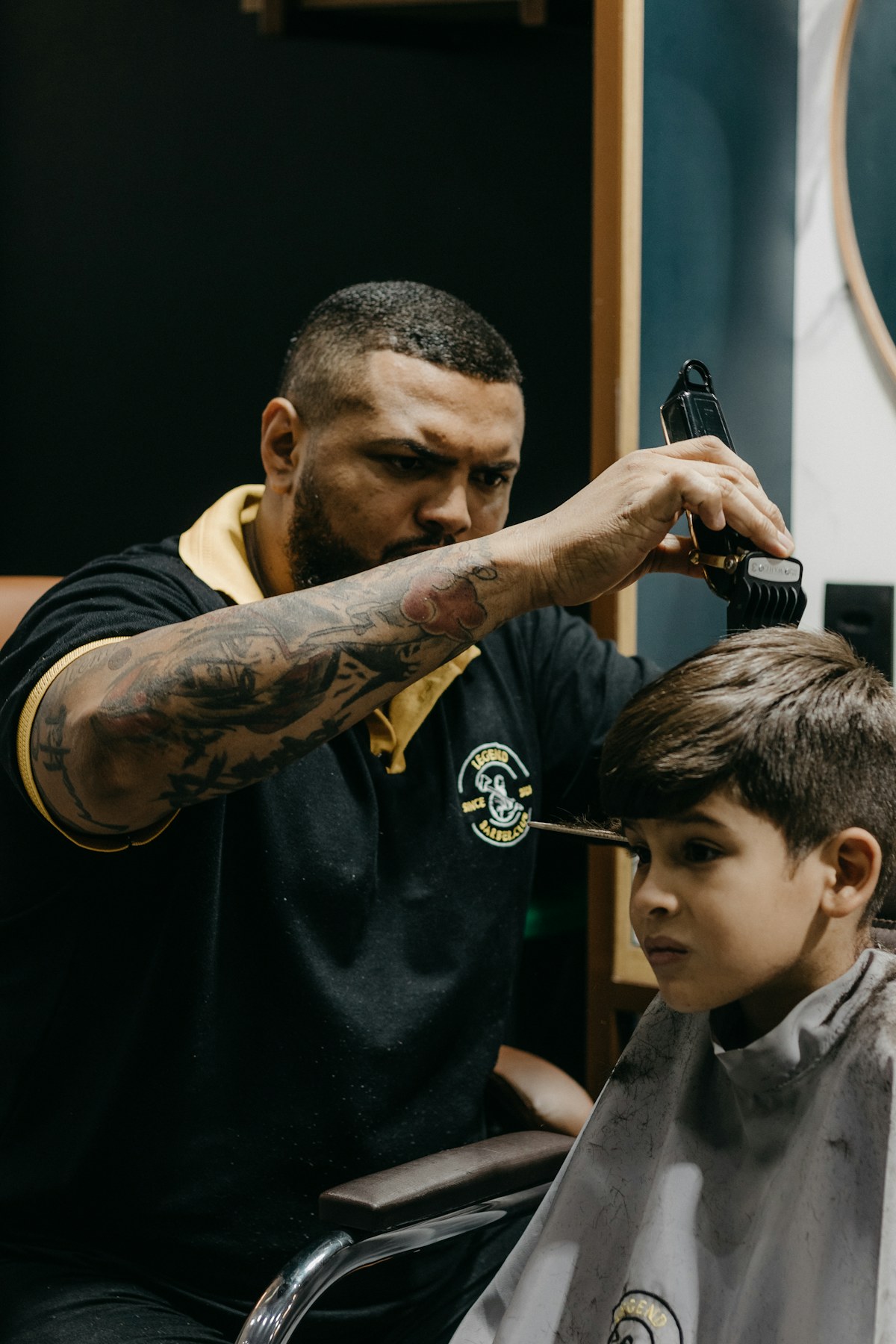 A barber carefully cutting a young boy’s hair
