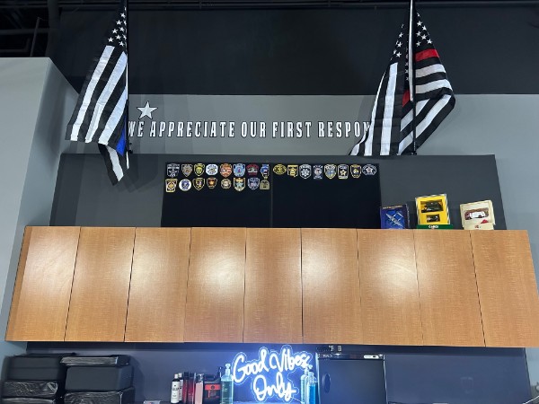 The in-shop wall honoring first responders with police and fire flags
